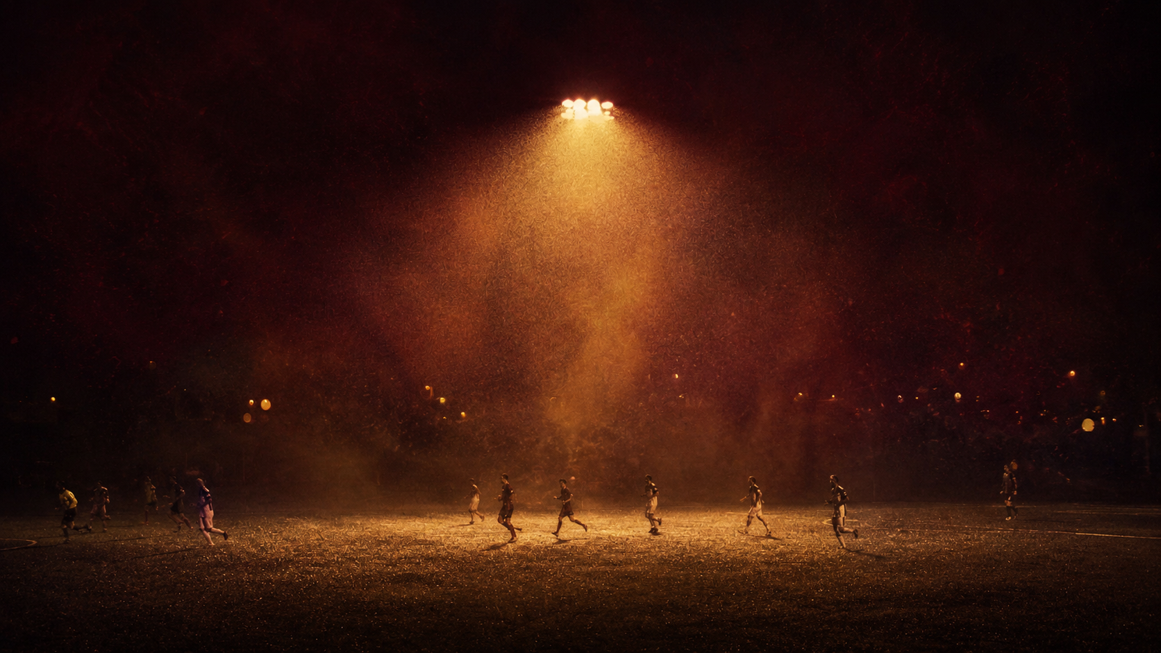 Football game on a field at night with players in silhouette